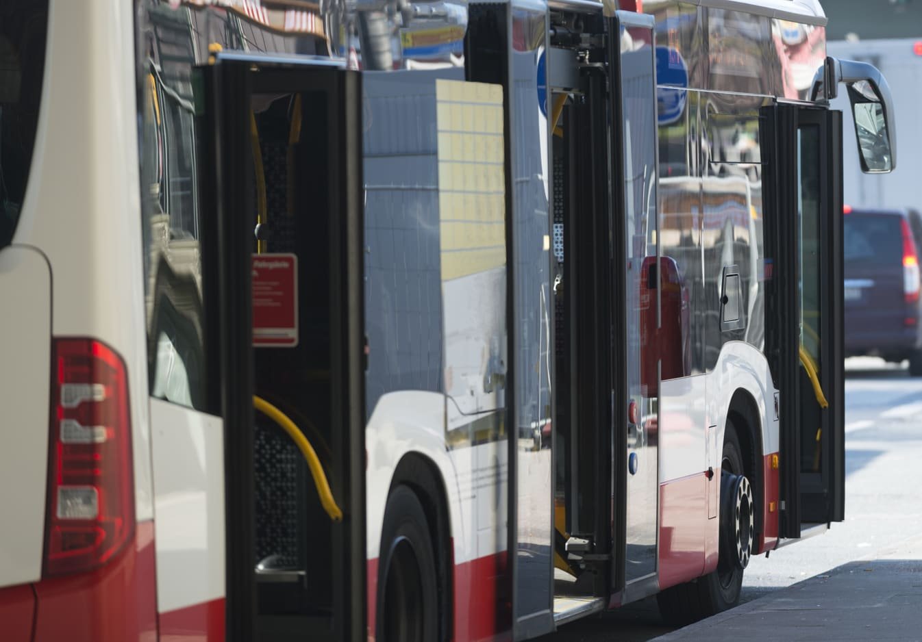 Ein weiß-roter Gelenkbus der Hamburger Hochbahn mit geöffneten Türen. Er symbolisiert die tägliche Mobilität in Hamburg und steht in Verbindung mit der PENSIONSKASSE der Hamburger Hochbahn Aktiengesellschaft -VVaG-.