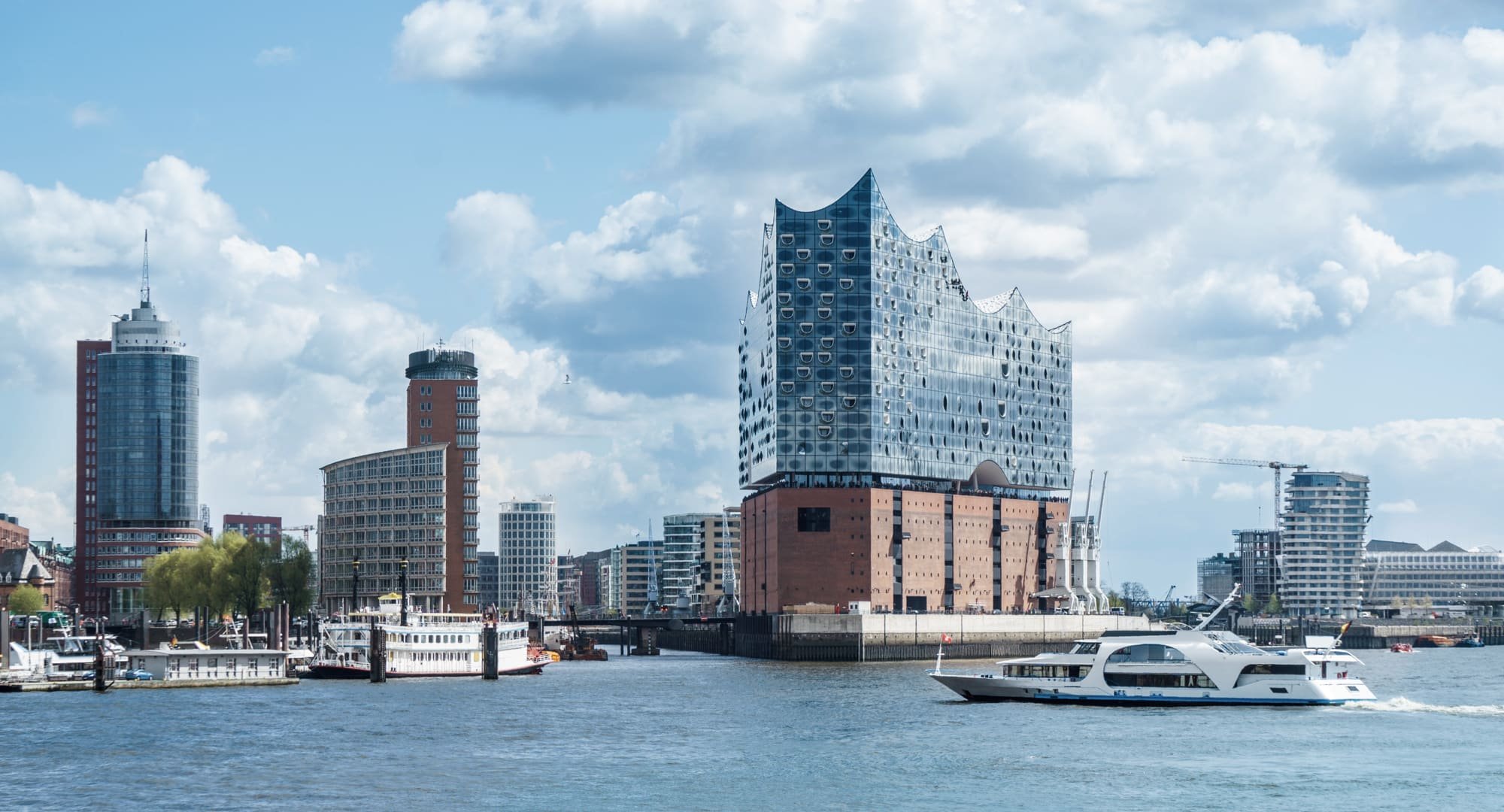 Blick über die Elbe auf die Elbphilharmonie und die moderne Hamburger Hafencity. Die PENSIONSKASSE der Hamburger Hochbahn Aktiengesellschaft -VVaG- ist seit Jahrzehnten ein sicherer Anker für die betriebliche Altersversorgung